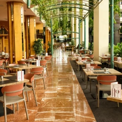Une grande salle de restaurant élégante sous une impressionnante structure de verrière cintrée.