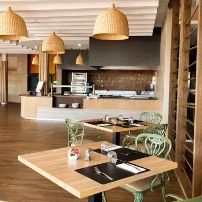 Un espace de restauration moderne avec des tables en bois clair et des chaises.