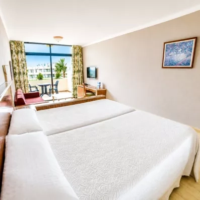 Une chambre lumineuse avec un grand lit double et une fenêtre donnant sur l'extérieur.