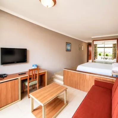 Un studio spacieux comprenant un coin salon avec canapé rouge et un espace nuit surélevé.