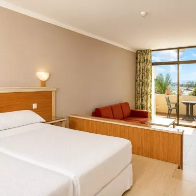 Une chambre climatisée offrant un accès direct à un balcon privé pour profiter de la brise marine.