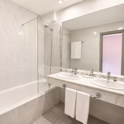 Une salle de bain immaculée et fonctionnelle équipée d'une baignoire avec paroi de douche vitrée.