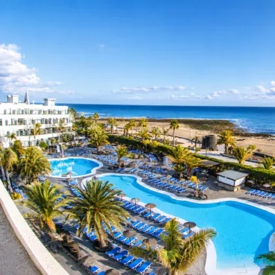 Une vaste piscine bordée de transats, avec l'océan à perte de vue en arrière-plan.