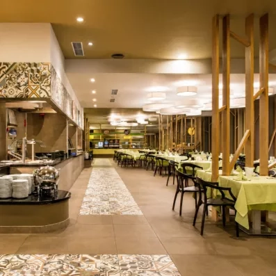 Une vaste salle de buffet lumineuse avec un long comptoir de service et de nombreuses tables nappées.