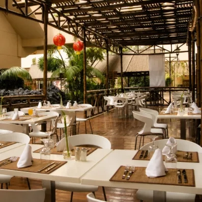Une terrasse de restaurant ombragée par une pergola en bois, offrant un cadre convivial pour dîner en extérieur.