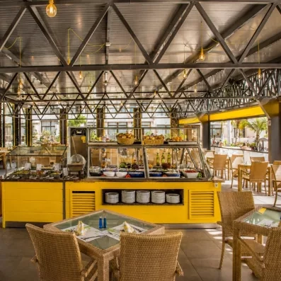 Un coin snack ou buffet extérieur sous une structure métallique industrielle avec un comptoir jaune vif.