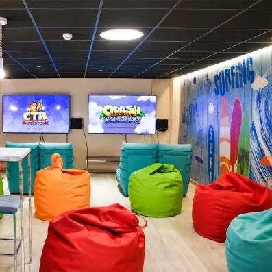 Une salle de jeux moderne,  équipée de poufs confortables et de grands écrans pour le divertissement.