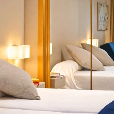 Un gros plan sur un lit confortable, reflété dans un miroir de chambre.