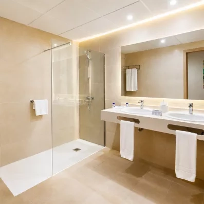 Une salle de bain moderne, dotée d'une grande douche à l'italienne et d'un long plan vasque.