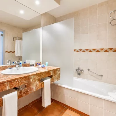 Une salle de bain avec un meuble en marbre brun, une baignoire et un grand miroir.