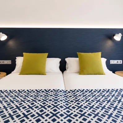 Un gros plan sur la tête de lit bleu marine, avec des coussins et des liseuses modernes de chaque côté.