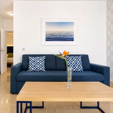 Un coin salon chaleureux décoré d'un tableau marin et de fleurs orangées.