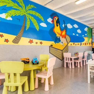 Un espace de jeux intérieur pour enfants avec des petites tables et chaises colorées.