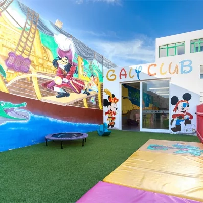 Une cour extérieure en pelouse et avec des décorations menant au miniclub.