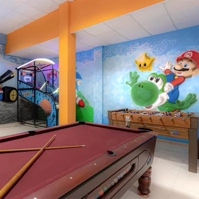 La salle de jeux montrant une table de billard au premier plan, un baby-foot.