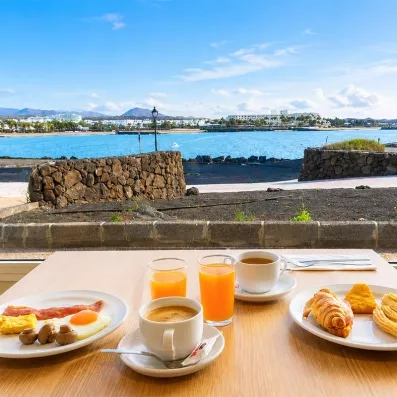 Un petit-déjeuner complet servi en terrasse avec une vue sur la mer et la côte.