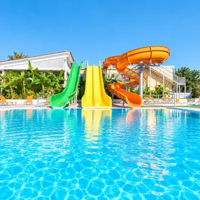 Piscine extérieur avec des toboggans aquatiques, de la végétation et des transats pour bronzer