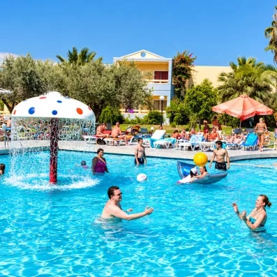 piscine avec fontaine champignons et des gens qui bronzent et jouent au ballon