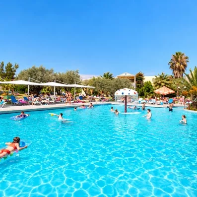 piscine extérieur avec fontaine colorée et un aqua parc au milieu et des gens qui nagent 