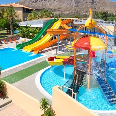 piscine, aqua park coloré, végétation autour et montagne au fond 
