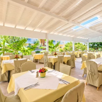restaurant extérieur couvert du soleil, avec des tables et des chaises en jaune pastel 