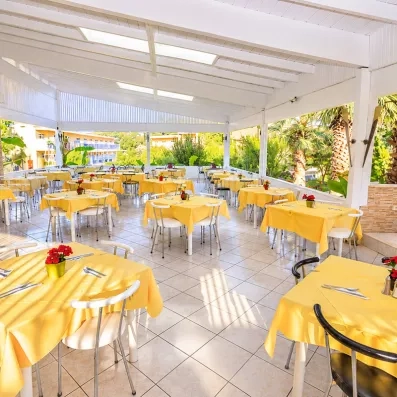 restaurant extérieur couvert du soleil, avec des tables et des chaises en jaune pastel 