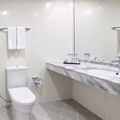 Une salle de bain, comprenant une baignoire avec paroi vitrée et un toilette.