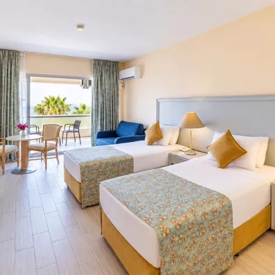 Une chambre spacieuse avec deux lits simples et une large baie vitrée ouvrant sur un balcon.