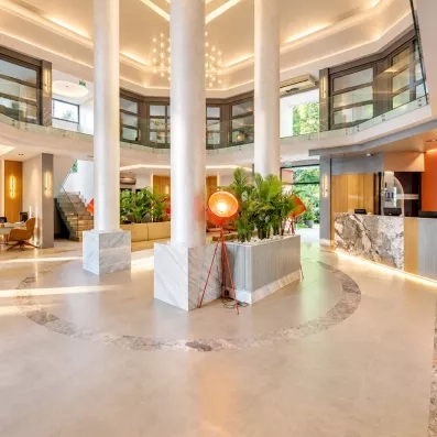Un hall d'entrée luxueux avec d'immenses colonnes blanches et un sol en marbre.