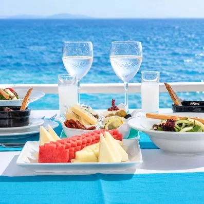 Une table dressée face à la mer avec des plats typiques grecs et turcs et des fruits.