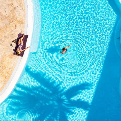Une vue aérienne montrant une personne nageant dans une piscine aux eaux turquoise.