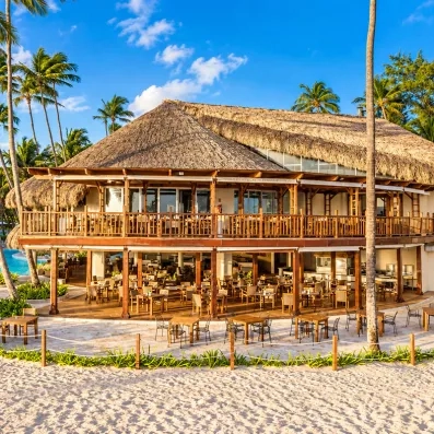 Un grand pavillon de plage, situé au bord de l'eau parmi les palmiers.