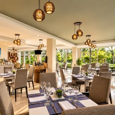 Une salle de restaurant moderne avec des tables dressées avec soin et des luminaires suspendus élégants.