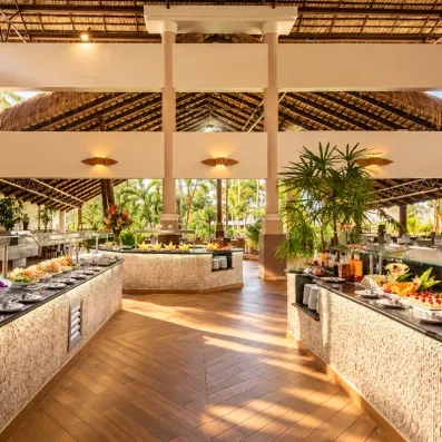 Un buffet spacieux et bien éclairé présentant un large choix de plats frais sous une haute structure de toit apparente.