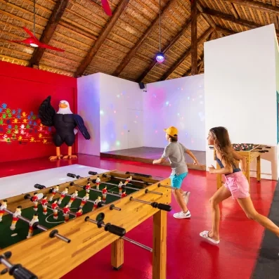 Une salle de jeux intérieure animée où des enfants s'amusent autour d'un baby-foot.
