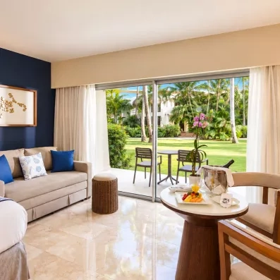 Une chambre moderne avec un canapé et une large baie vitrée ouvrant sur un jardin.