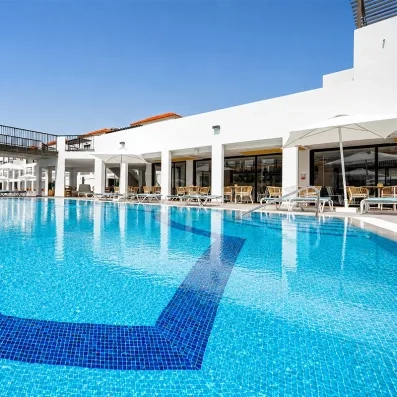 Une grande piscine principale avec une passerelle en arrière-plan et des façades de bâtiments modernes.
