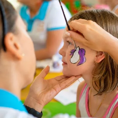 Une enfant se faisant peindre sur la joue lors d'une activité de maquillage.