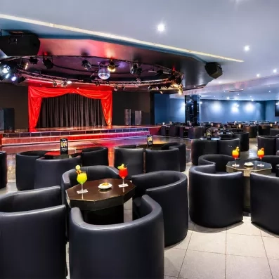 Une salle de spectacle spacieuse avec une scène éclairée et des fauteuils.