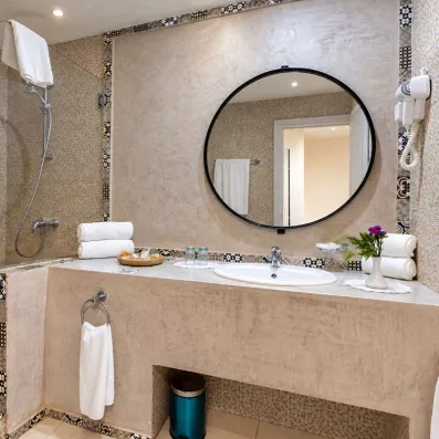 Salle de bain en tadelakt avec grand miroir rond à l'hôtel tout inclus Welcome Meridiana Djerba