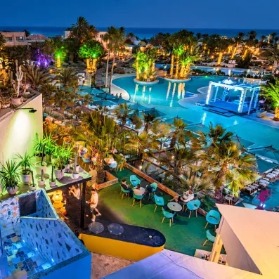 Vue panoramique sur les piscines illuminées de hôtel tout inclus Welcome Meridiana Djerba