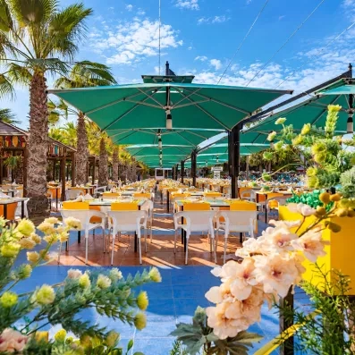Restaurant extérieur ombragé avec parasols turquoise au Welcome Meridiana Djerba 