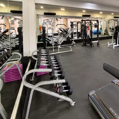 salle de sport bien équipée et avec des miroirs sur les murs qui entoure