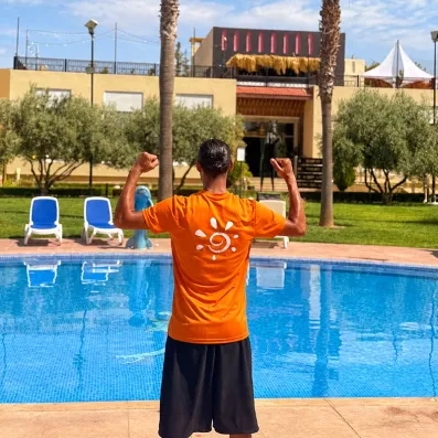 Animateur Mondi Club t shirt orange piscine bleue ciel bleue végétation tobogan