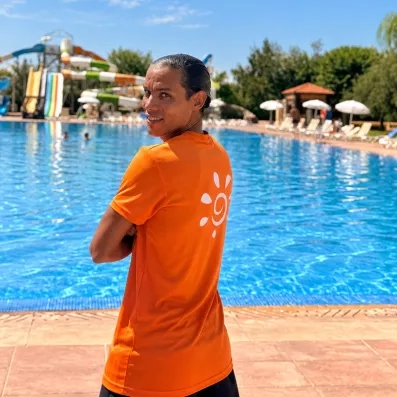 Animateur Mondi Club t shirt orange piscine bleue ciel bleue végétation tobogan