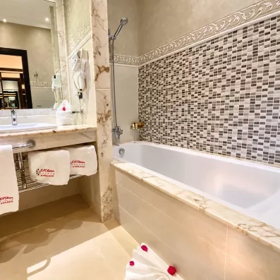 salle de bain avec lavabo intégré et un miroir juste en dessus et une baignoire avec vitre et des serviettes