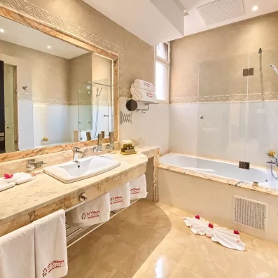 salle de bain avec une vasque avec un lavabo intégré et un grand miroir, juste à côté il y a la baignoire