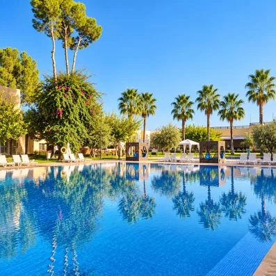 piscine avec tranastas et parasols entourée d'arbres