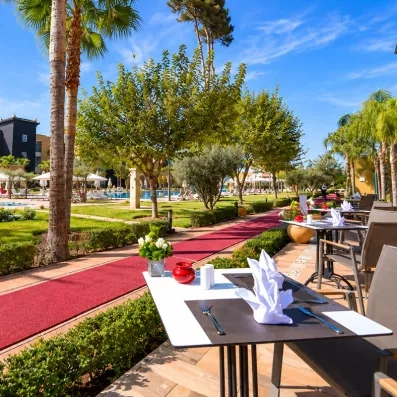 café  extérieur dans une terrasse séparé par une allée et au fond un jardin et la piscine