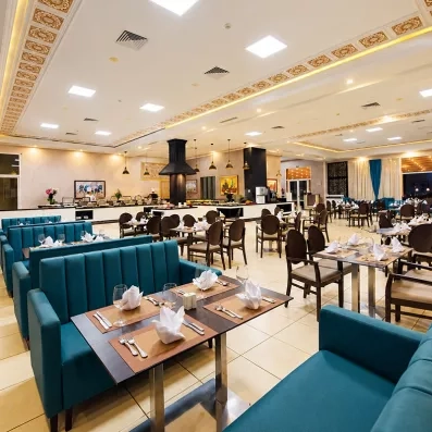 restaurant de l'hôtel avec tables et chaises avec des accoudoirs, juste en face des baies vitrés 
